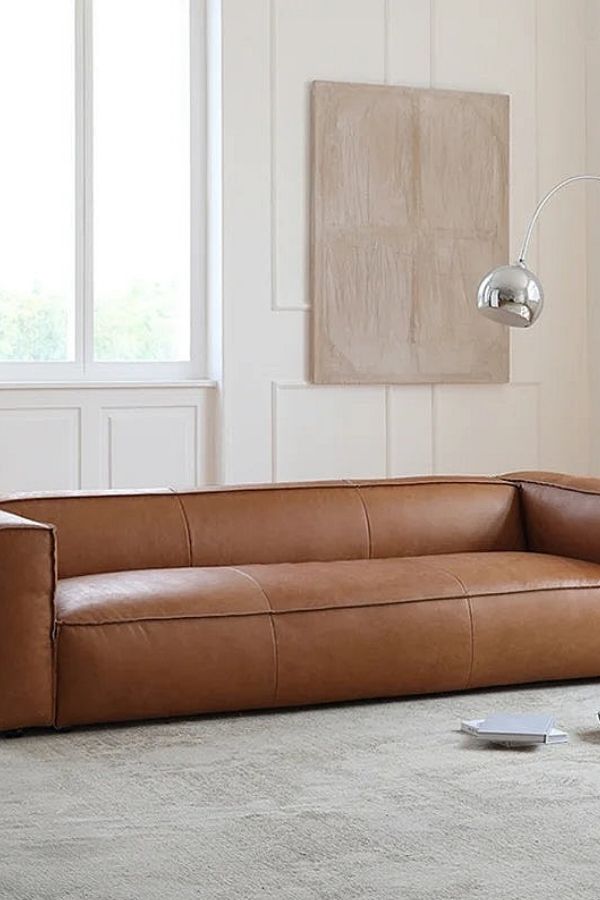 Boho furniture ideas: Rich tan leather sofa, textured pillows, vibrant decor.
