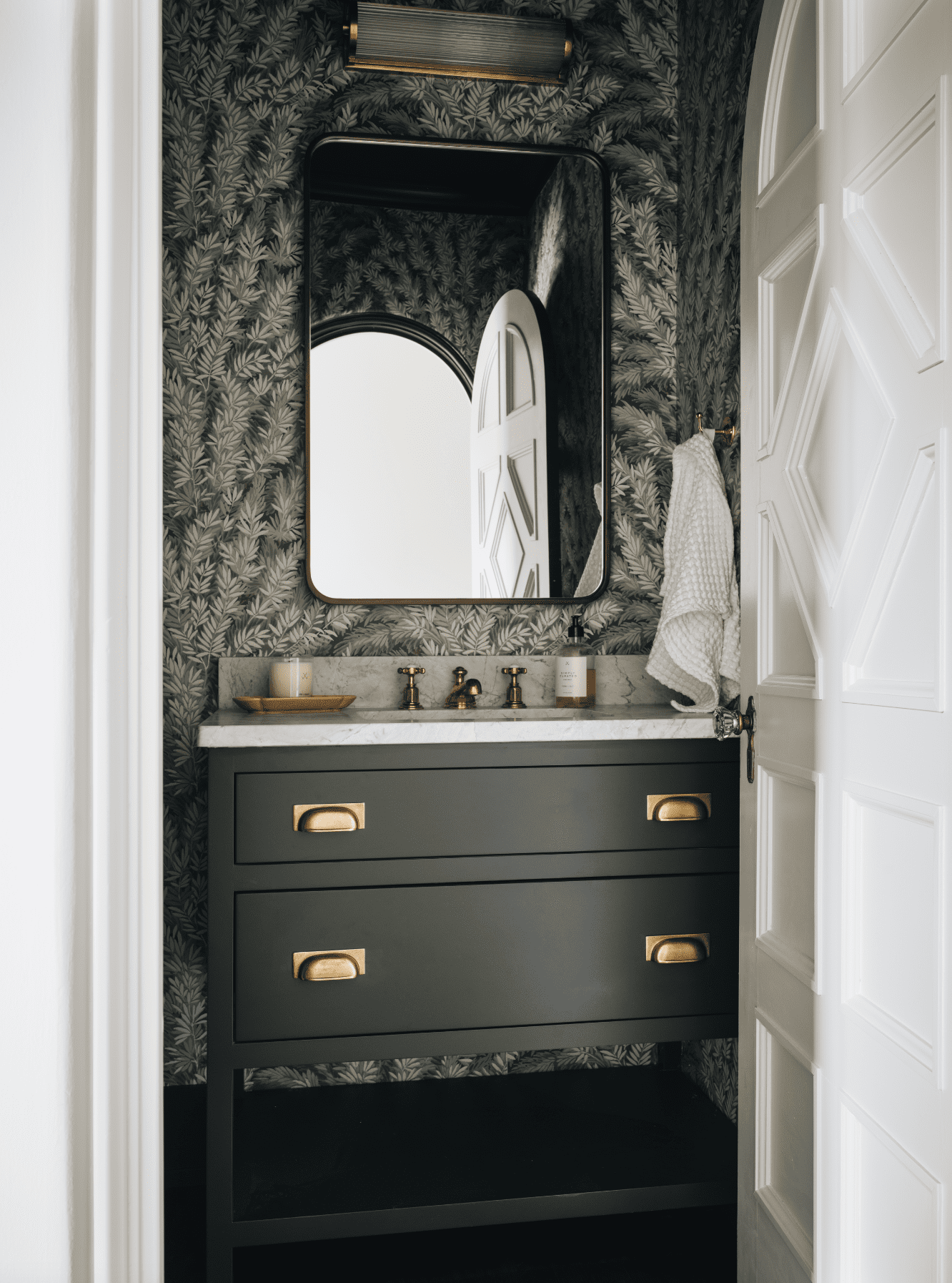 Dark Vanity With Leafy Wallpaper Creates a Moody Powder Room