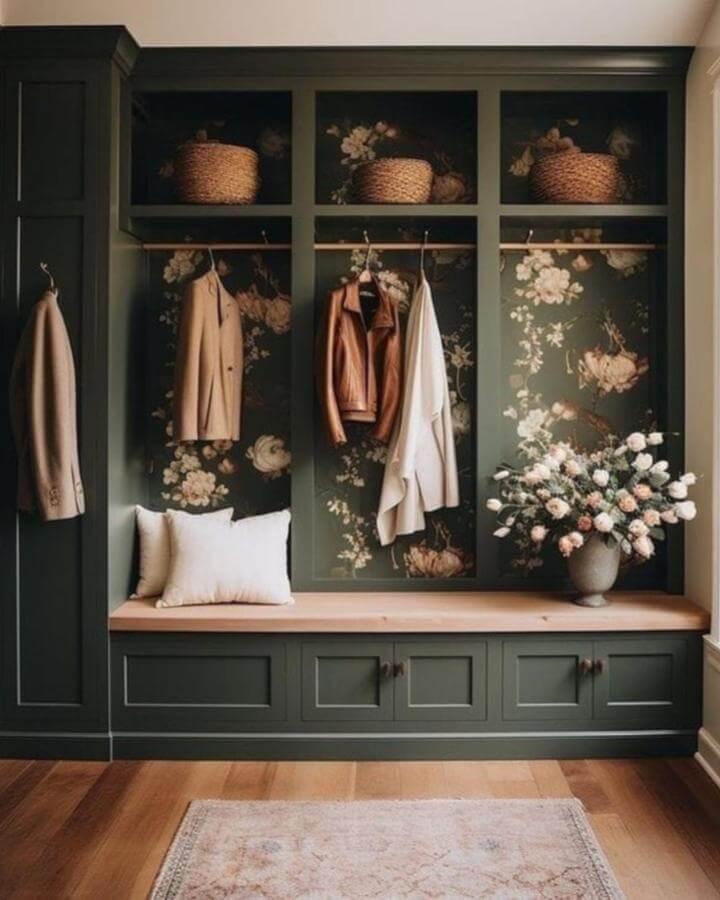 Deep forest green mudroom bench with floral wallpaper and woven baskets from @homestylejoy creating a warm, inviting entry space.
