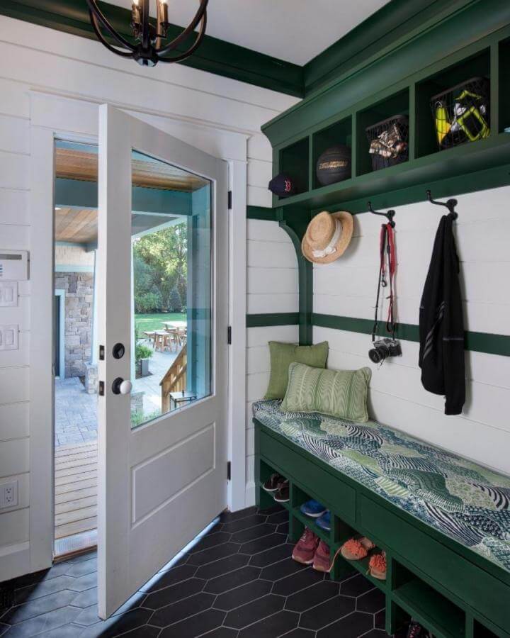 Deep forest green mudroom bench with patterned cushion and black hex tile floor from @natreaphotography shows stylish green mudroom ideas.