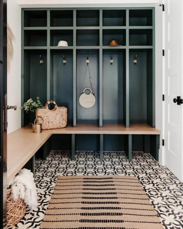 Deep forest green cubby mudroom from @raebarber_ with patterned tile floor and natural wood bench for organized entryway style
