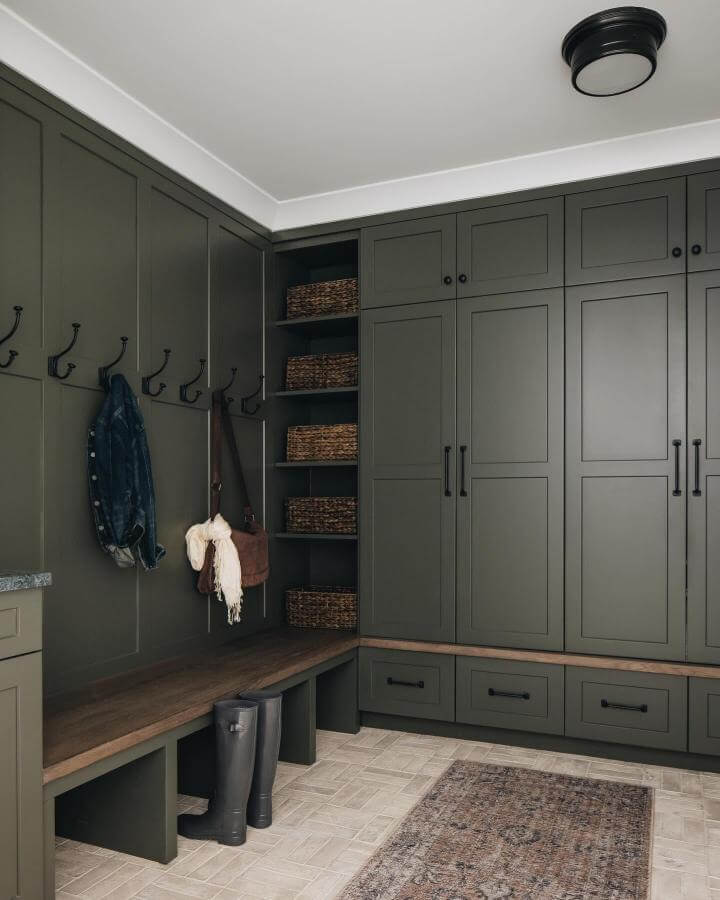 Olive green cabinetry and wood bench from @urbanehome. Stylish and practical green mudroom ideas with cozy seating and storage.