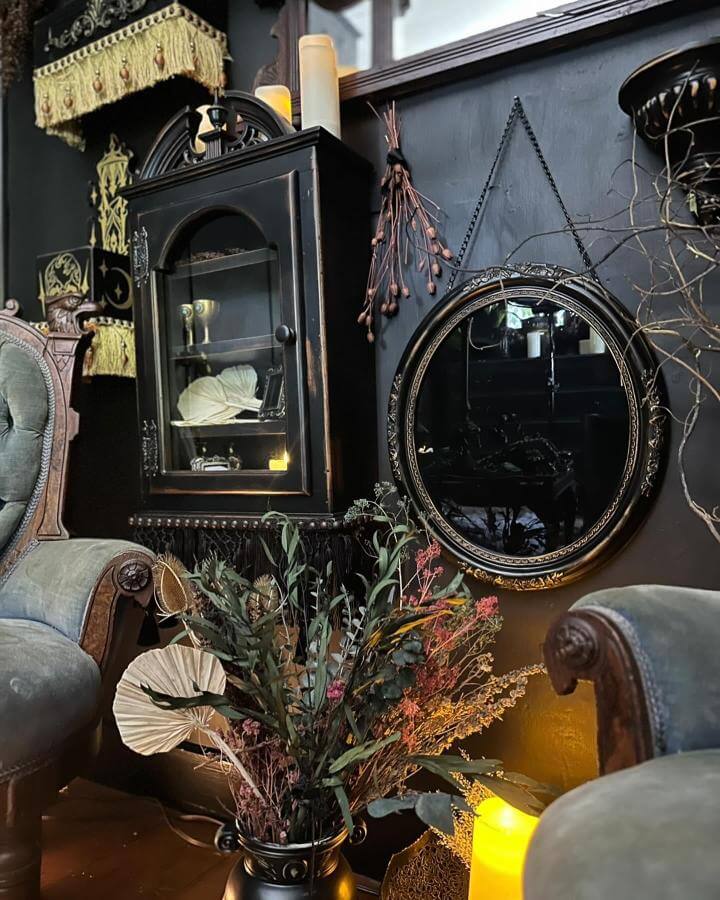 Ornate black Victorian display cabinet from @immortal_curio_company. Gothic styling with autumn florals and mysterious collectibles.