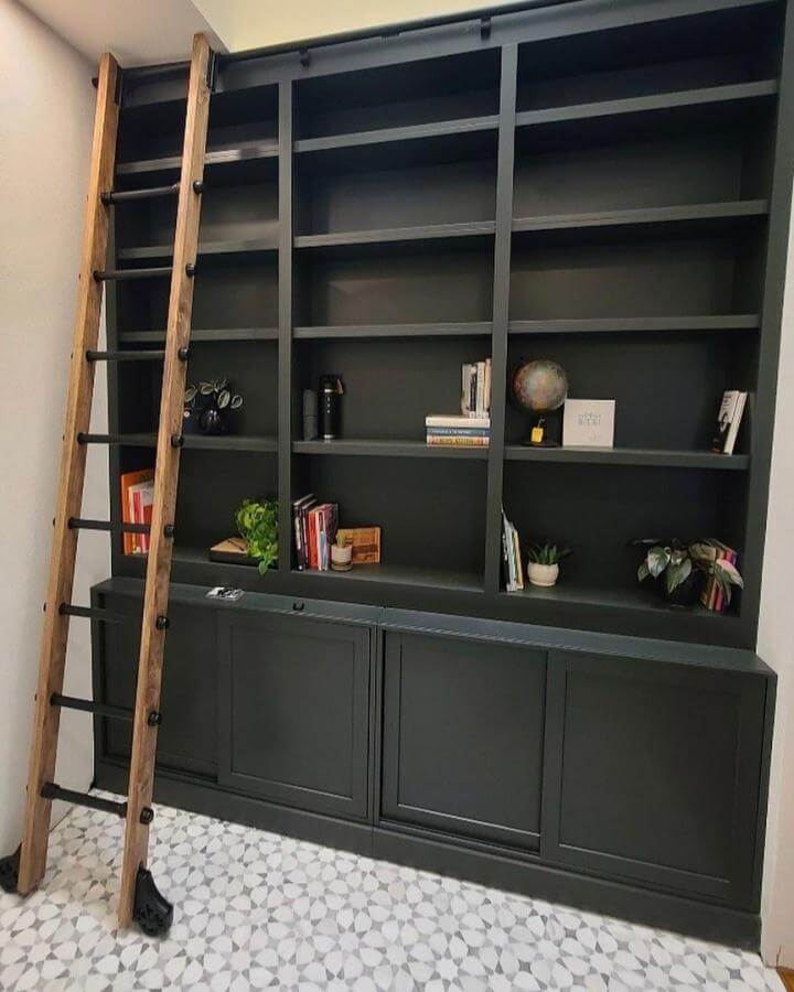 Dark green painted storage cabinet from @redunnhomes with wooden ladder and styled shelving display.