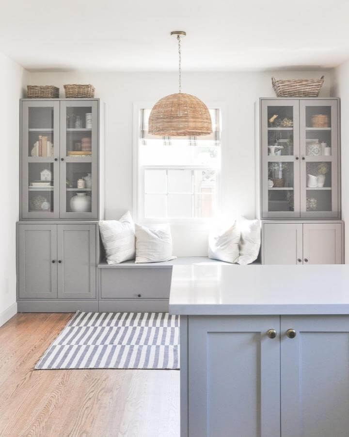 Gray painted cabinet storage from @hydrangeatreehouse with built-in window seat and wicker basket styling.