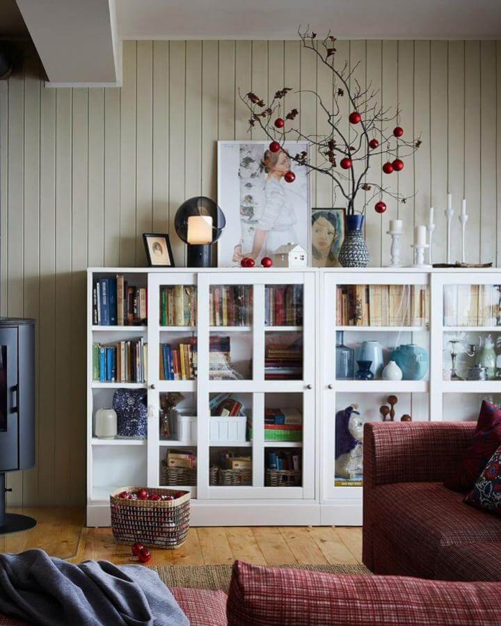 White glass door cabinet featuring ikea havsta hacks & ideas from @ikeadeutschland. Holiday styling with books and ornaments.