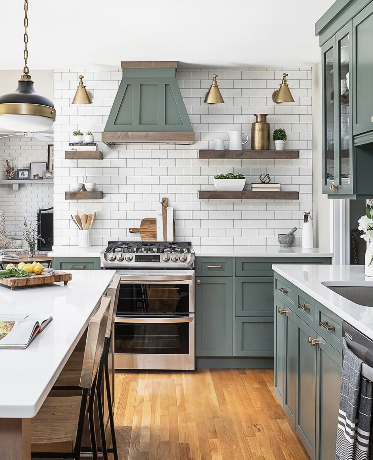 Sage green range hood with wood trim adds rustic charm