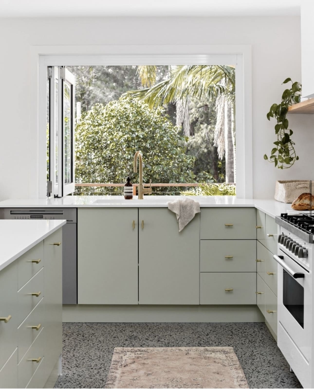 Sage cabinets and brass hardware create a warm kitchen