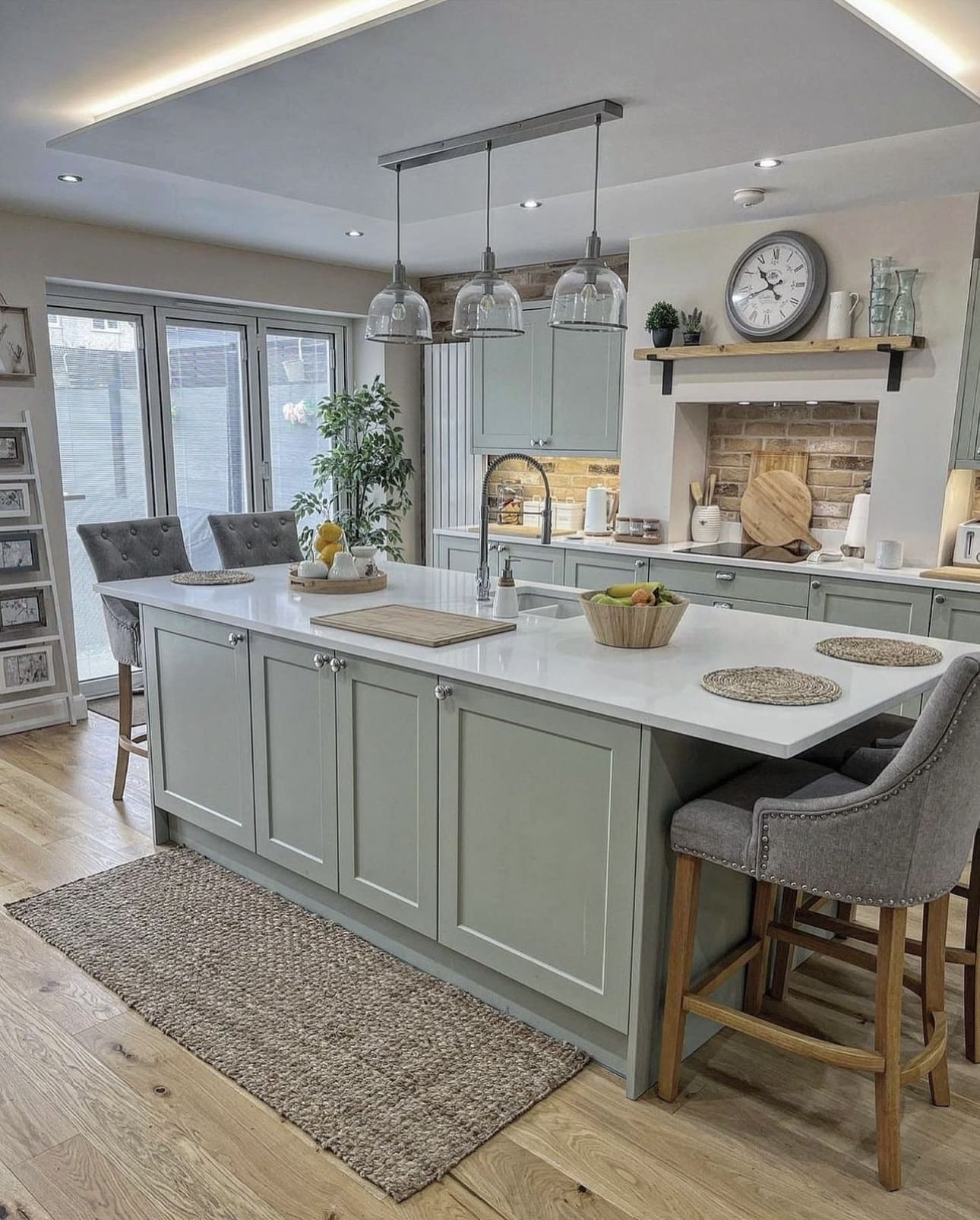 Sage green island cabinets with a cantilevered breakfast bar extension