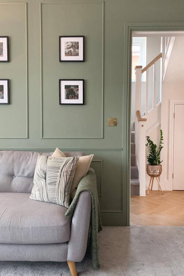 Green living space with wooden panels, cozy furniture, natural lighting.
