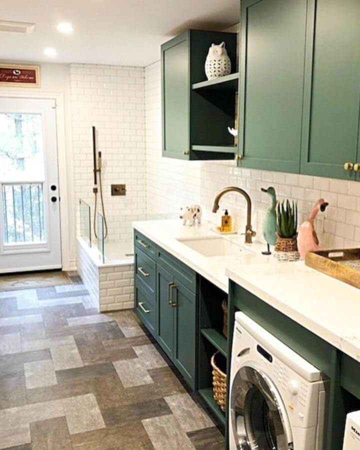 Emerald green cabinetry and white subway tile mudroom dog wash ideas from @hartley_built featuring brass hardware and a raised tile dog washing station.