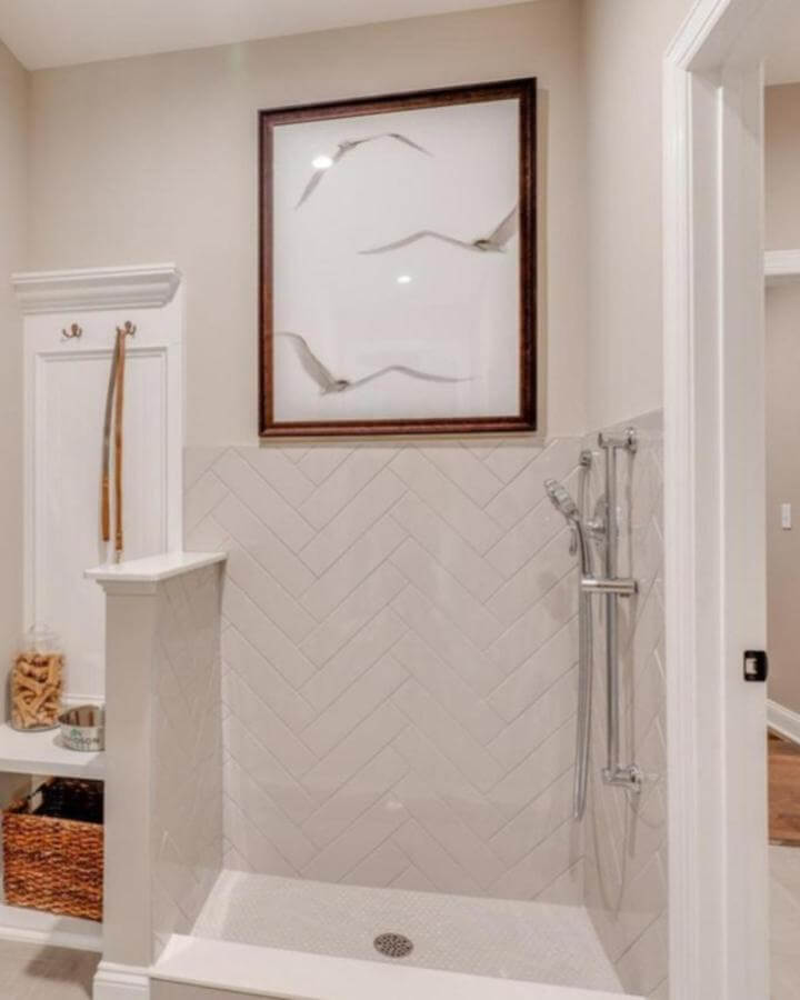 Neutral herringbone tile mudroom dog wash area with chrome shower and framed bird artwork by @newhomesandideas bright and clean pet care space