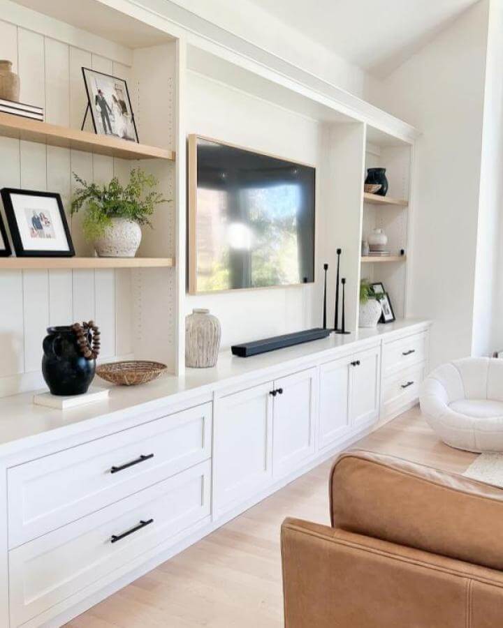 White media center with natural wood floating shelves and black hardware from @eyeforpretty showcasing ikea media center hacks & ideas.