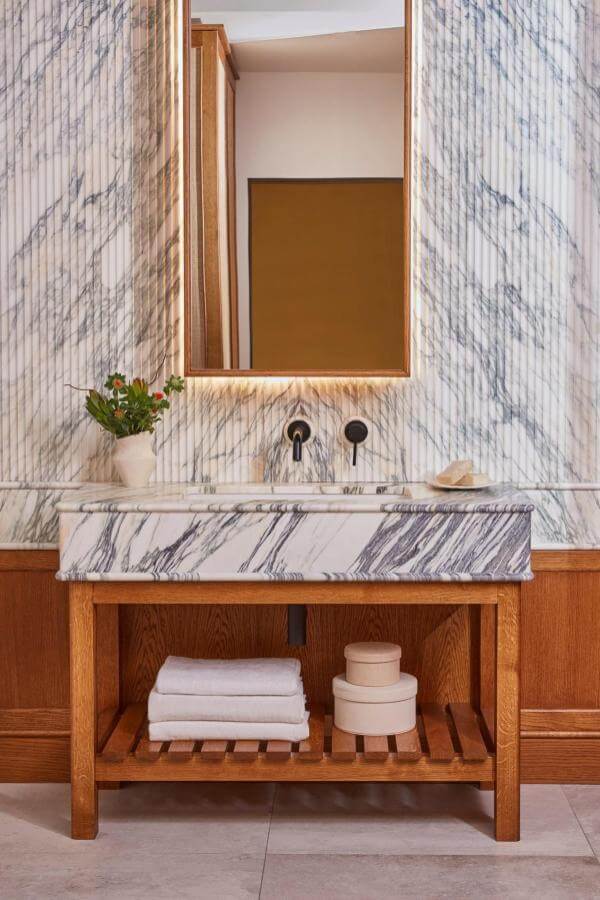 White marble sink meets wooden accents from @blakesldn, creating an elegant contrast in a contemporary bathroom.