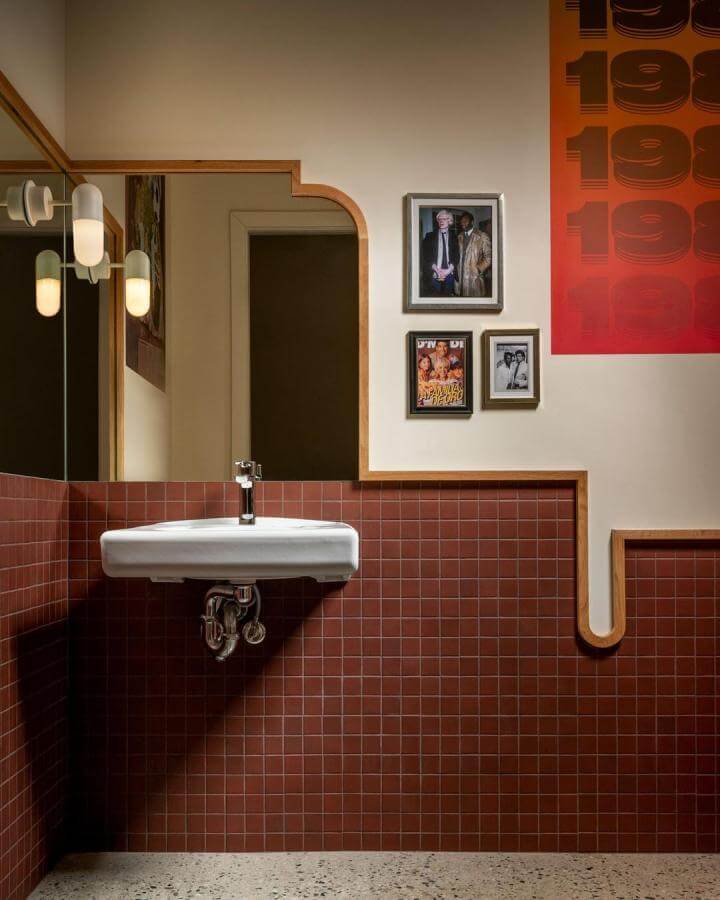 Terracotta tiled bathroom walls with unique wooden trim and vintage framed photos by @conradbrownphoto⁠ ⁠ bright and warm design.