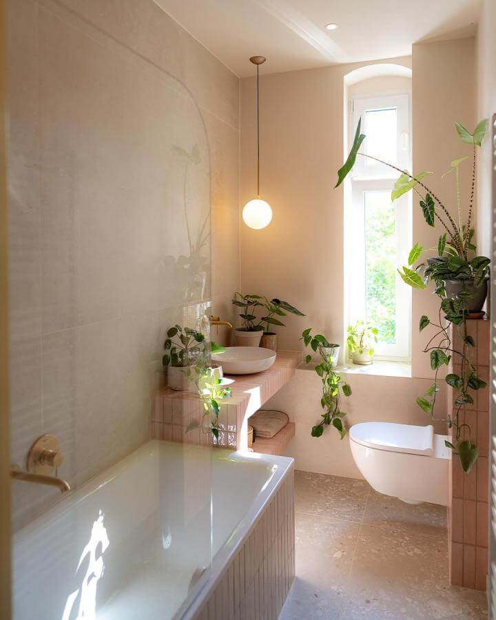 Soft pink tiled bathroom with plants and natural light by @ranasamonehome showing clever space use and warmth.